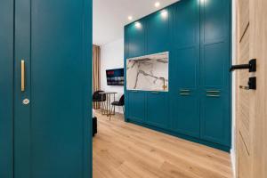 a room with blue cabinets and a wooden floor at GreenRoom Kunigiškės in Palanga