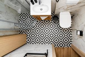 a bathroom with a white sink and a black and white tiles at GreenRoom Kunigiškės in Palanga