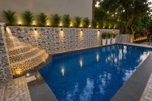 a swimming pool with lights next to a wall at Strand Resort in Lonavala