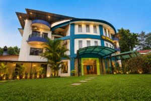 a blue and white building with a green yard at Strand Resort in Lonavala