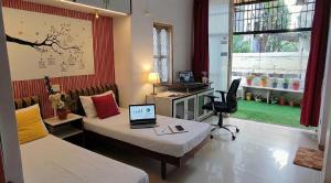 a room with two beds and a desk with a laptop at Homeland Stay in Ahmedabad