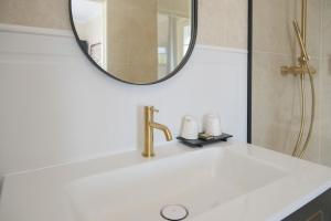 a bathroom sink with a gold faucet and a mirror at Best Western Le Cheval Blanc -Vue sur le port-plein centre ville in Honfleur