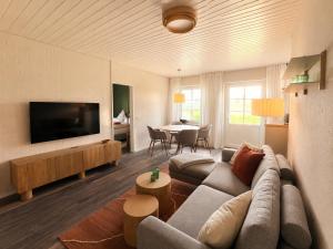 a living room with a couch and a tv and a table at elf-36 Apartmenthaus Bensersiel in Bensersiel