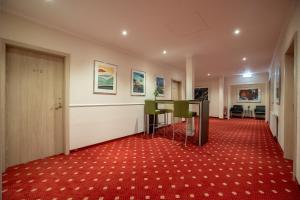 a hallway with a table and chairs on a red carpet at Hotel Union Salzwedel in Salzwedel