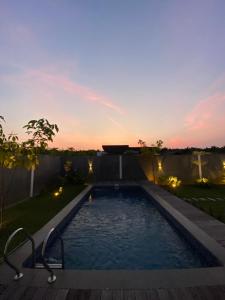 a swimming pool in a backyard at sunset at Svaha Ubud Villas in Siantan