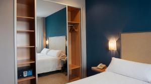 ein Hotelzimmer mit Bett und Spiegel in der Unterkunft Apartamentos Vértice Sevilla Aljarafe in Bormujos + 31 Fotos