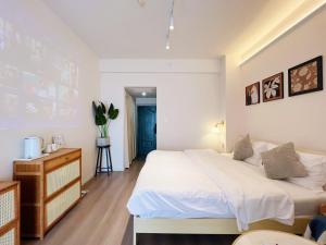 a bedroom with a large white bed and a dresser at Tulips apartment in Chengdu
