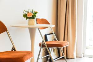 a table with a vase of flowers and two chairs at Tulips apartment in Chengdu