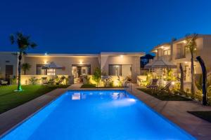 a swimming pool in front of a house at night at Oasis Luxury Suites in Kolymbia +103 photos