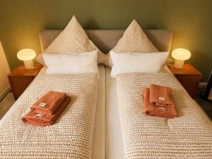 two beds with brown and white sheets and pillows at elf-36 Apartmenthaus Bensersiel in Bensersiel