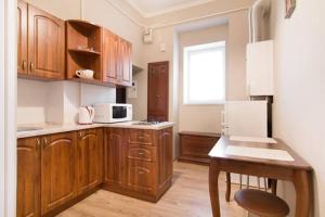 une cuisine avec des placards en bois, une table et une fenêtre dans l'établissement Apartment on Deribasovskaya 18, à Odessa