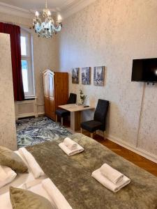 a room with a bed and a table and a chandelier at Hotel Pension Bella in Berlin
