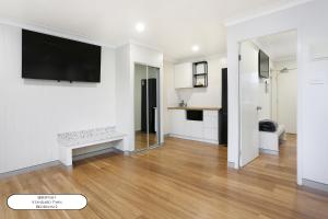 a living room with white walls and a flat screen tv at Surf Beach Motel Port in Port Macquarie