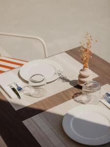 a table with plates and glasses on a wooden table at Cavo Notos Beach Hotel in Kavos
