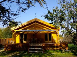 una casa amarilla con porche y escaleras a ella en Chalet au Domaine de la Goujonne en Saint-Sauveur-lès-Bray