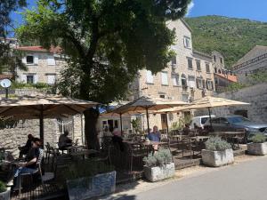 a group of people sitting at tables under umbrellas at Apartment Forteca Lux in Perast