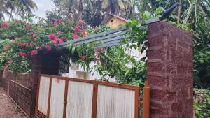 a fence with pink flowers and a house at Bhatye Beach Resort MTDC in Ratnagiri