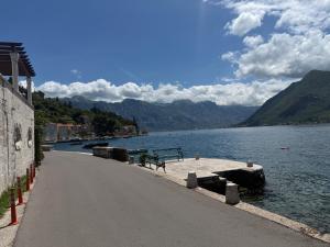 a road next to a lake with a bench at Apartment Forteca Lux in Perast