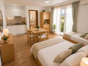 a bedroom with two beds and a table and a kitchen at Apartments Butkovic in Hvar