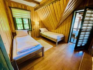 a bedroom with two beds in a wooden room at Agroturystyka Na Górze - Obrocz 116A in Obrocz