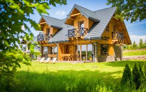 a log home with a metal roof and a deck at Bieszczadzka Hawira - Domki w Centrum przy Jeziorze z Widokiem dla Rodzin in Polańczyk +58 photos