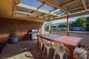 a patio with a wooden table and chairs and a grill at Kingscote Getaway Kangaroo Island in Kingscote +14 photos