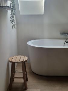 a bath tub in a bathroom with a wooden stool at Muntershof in Zottegem