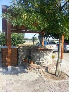 a pavilion with a stone wall and a tree at Agriturismo Bufaleria in Scanzano