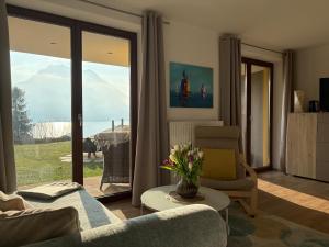 ein Wohnzimmer mit Sofa, Sessel und Fenster in der Unterkunft Inspiration - zwei Terrassen, Seeblick, privater Garten in Altmünster