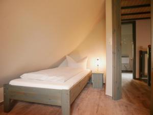 a bedroom with a bed with white sheets and a lamp at Poeler Inselhaus in Kaltenhof