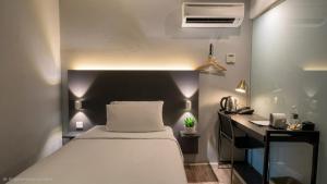 a bedroom with a white bed and a desk with a fan at The Leverage Business Hotel - Rawang in Rawang