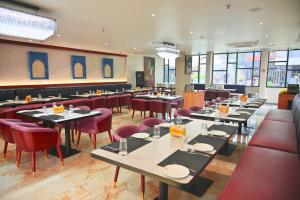a dining room with tables and red chairs at The Park Inn in Jhārsuguda