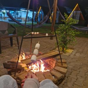 a person is sitting around a fire in a tent at 2210 CadBox Suíte, Hidro, Churrasqueira, Cozinha Privativo in Sao Jose do Rio Preto