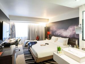 a hotel room with a large bed and a desk at Novotel London Tower Bridge in London +184 photos