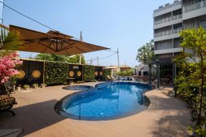 a swimming pool with an umbrella next to a building at The Park Inn in Jhārsuguda