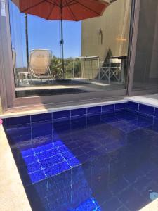 a blue tiled pool with a table and an umbrella at FinIQ Boutiq Studios in Foiníki