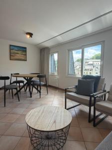 a living room with chairs and a table and windows at Hotel LA PLAGE in Bouillon