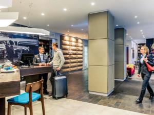 a group of people standing at a counter with a suitcase at Mercure Hotel & Residenz Berlin Checkpoint Charlie in Berlin