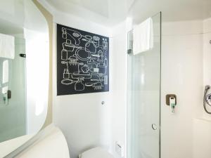 a bathroom with a black and white painting on the wall at ibis Leicester in Leicester