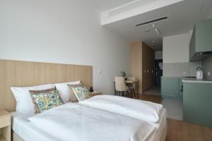 a bedroom with a large white bed and a kitchen at Aparthotel Symphony Krakowska 35 by INA in Wrocław