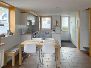 a kitchen with a wooden table and white chairs at Steuerbord in Prerow +18 photos