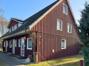 a red barn with a black roof at Steuerbord in Prerow