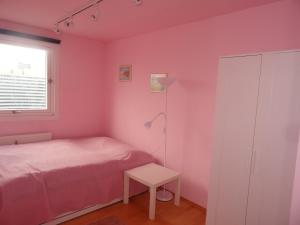 um quarto com paredes cor-de-rosa, uma cama e uma mesa em Flat UNO City em Viena