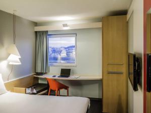 a hotel room with a bed and a desk with a laptop at Hotel ibis Porto Sao Joao in Porto