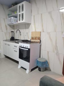 a small kitchen with a stove and a sink at Aluguel casa azul in Capão da Canoa