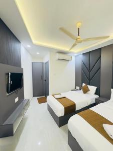 a hotel room with two beds and a flat screen tv at Hotel Lime Wood Mangaluru in Mangalore