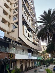a large building with a palm tree in front of it at Hotel Lime Wood Mangaluru in Mangalore