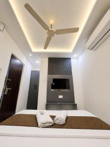 a bedroom with a ceiling fan and a bed with two towels at Hotel Lime Wood Mangaluru in Mangalore