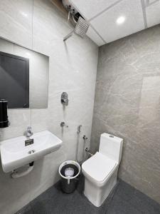 a bathroom with a white toilet and a sink at Hotel Lime Wood Mangaluru in Mangalore