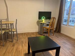 a living room with a table and chairs and a tv at Lovely Amour Hyper Centre in Caen